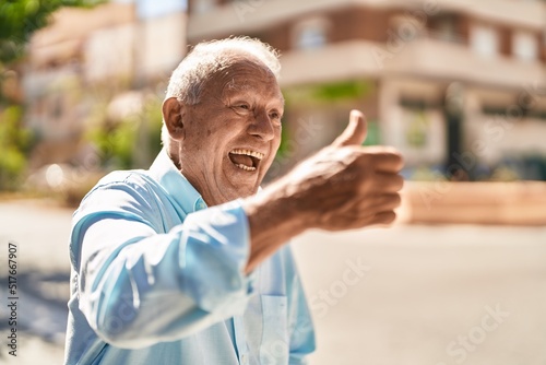Senior grey-haired man smiling confident doing ok sign with thumb up at street © Krakenimages.com