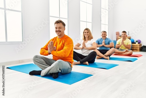 Group of middle age people training yoga at sport center.