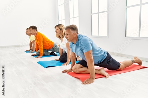 Group of middle age people concentrate training yoga at sport center.
