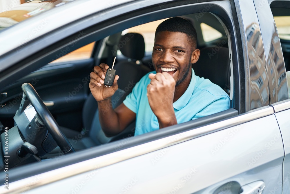 Young african american man holding key of new car with cheerful expression at street