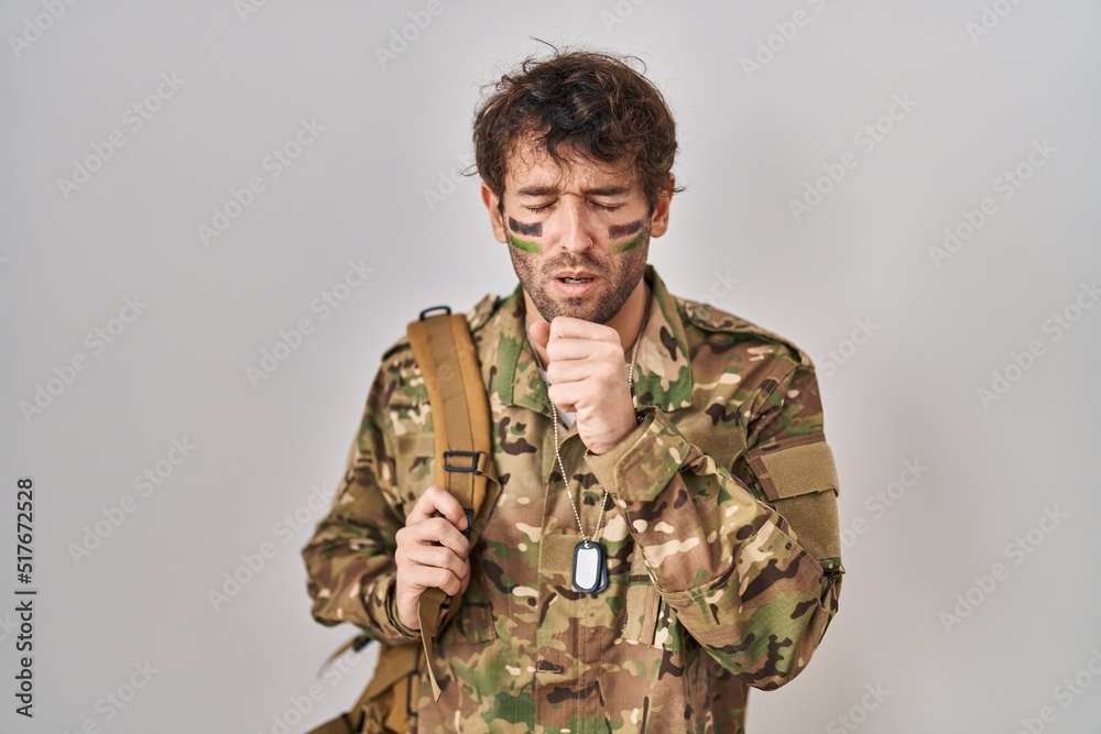 Hispanic young man wearing camouflage army uniform feeling unwell and coughing as symptom for cold or bronchitis. health care concept.