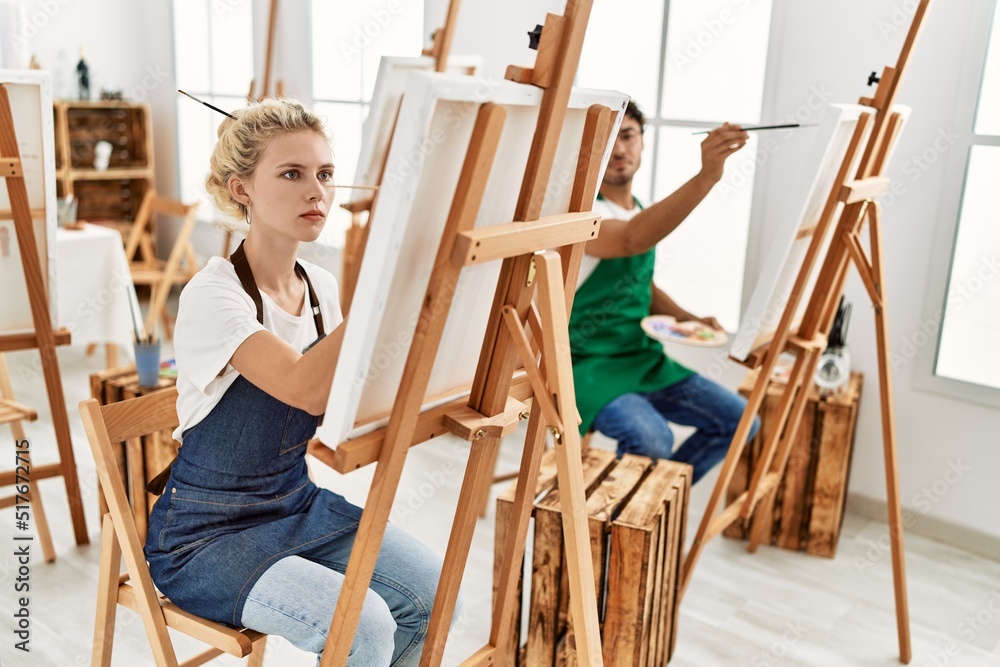 Young artist couple concentrated painting at art studio.