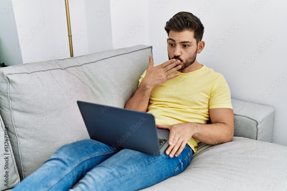 Young hispanic man having video call lying on the sofa at home. Young hispanic man having video call lying on the sofa at home.