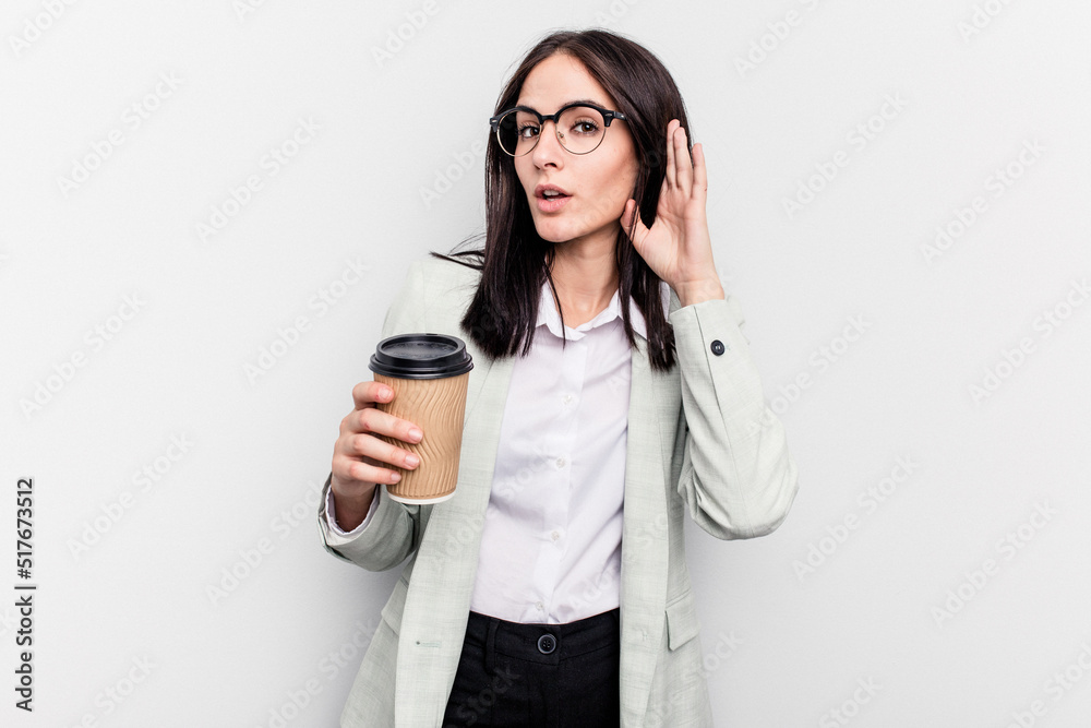 Young business caucasian woman holding takeaway coffee isolated on white background trying to listening a gossip. Young business caucasian woman holding takeaway coffee isolated on white background trying to listening a gossip.
