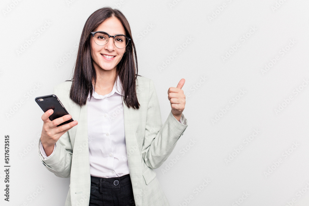 Young business caucasian woman holding mobile phone isolated on white background smiling and raising thumb up