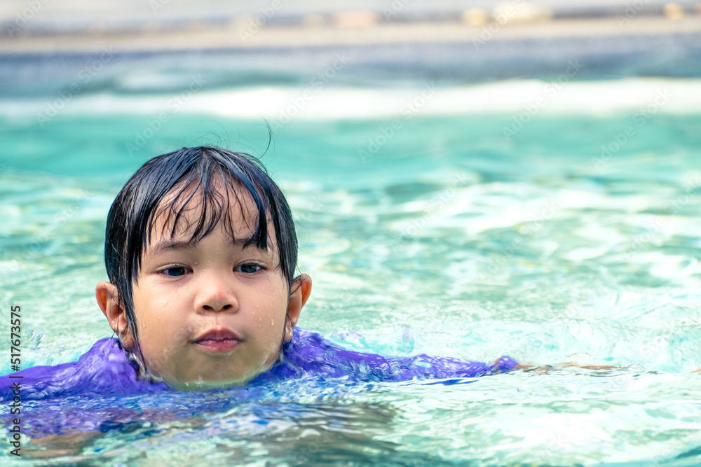 Cute asian girl floating in the water in a swimming pool Cute asian girl floating in the water in a swimming pool