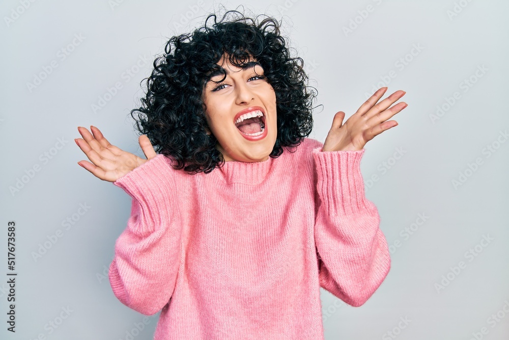 Young middle east woman wearing casual clothes celebrating crazy and amazed for success with arms raised and open eyes screaming excited. winner concept Young middle east woman wearing casual clothes celebrating crazy and amazed for success with arms raised and open eyes screaming excited. winner concept