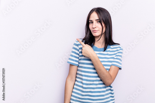 Young caucasian woman isolated on pink background smiling and pointing aside, showing something at blank space.