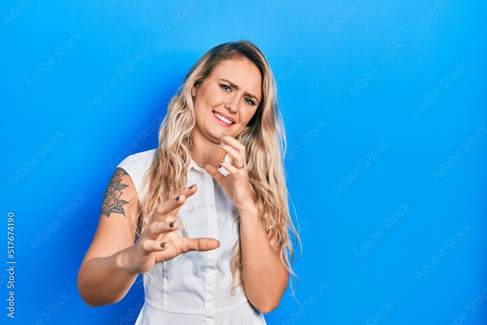 Beautiful young blonde woman wearing casual white shirt disgusted expression, displeased and fearful doing disgust face because aversion reaction. with hands raised Beautiful young blonde woman wearing casual white shirt disgusted expression, displeased and fearful doing disgust face because aversion reaction. with hands raised