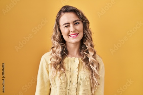 Young caucasian woman standing over yellow background winking looking at the camera with sexy expression, cheerful and happy face. © Krakenimages.com