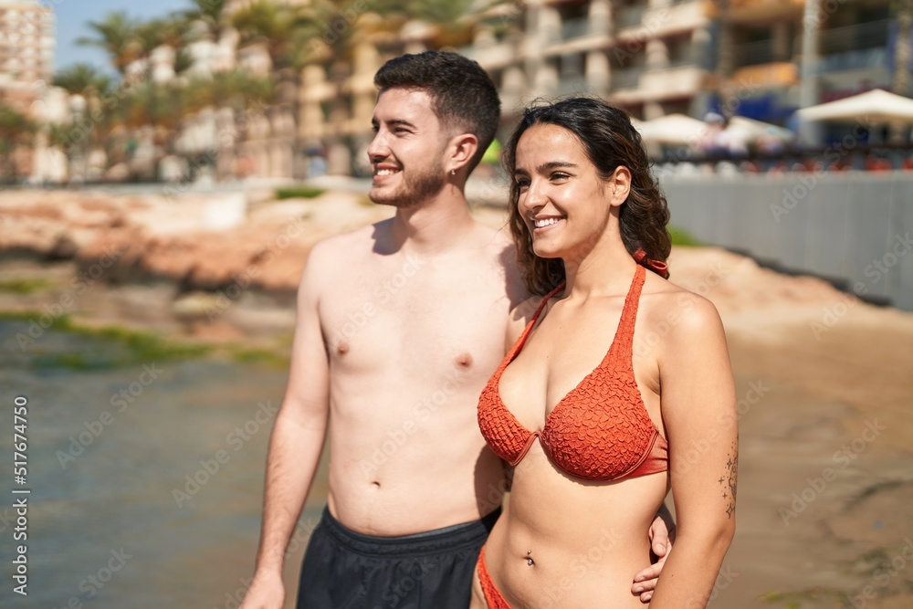 Young hispanic couple tourists wearing swimsuit hugging each other at seaside Young hispanic couple tourists wearing swimsuit hugging each other at seaside