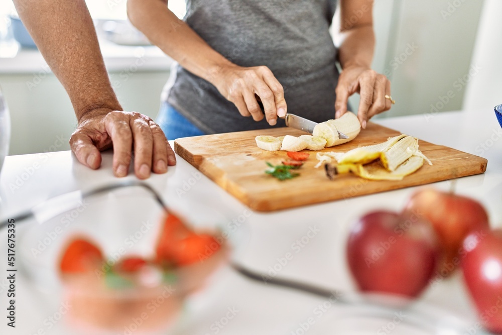 Couple cooking smoothie cutting banana at the kitchen.