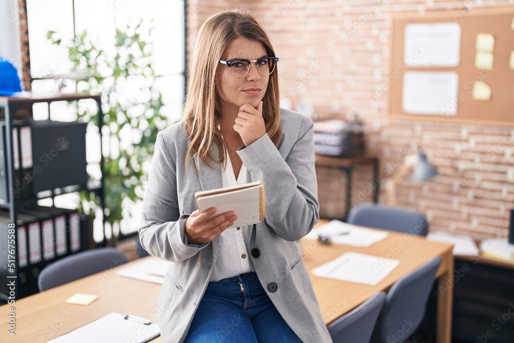 Young hispanic woman working at the office wearing glasses looking confident at the camera smiling with crossed arms and hand raised on chin. thinking positive. Young hispanic woman working at the office wearing glasses looking confident at the camera smiling with crossed arms and hand raised on chin. thinking positive.