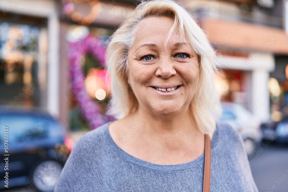 Middle age blonde woman smiling confident standing at street