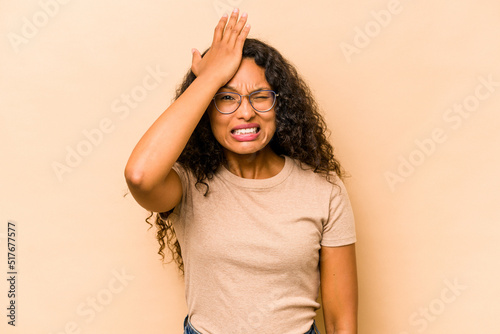 Young hispanic woman isolated on beige background forgetting something, slapping forehead with palm and closing eyes.