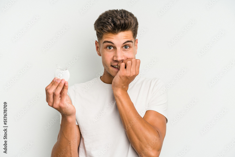 Young caucasian man hand sling isolated on white background biting fingernails, nervous and very anxious. Young caucasian man hand sling isolated on white background biting fingernails, nervous and very anxious.
