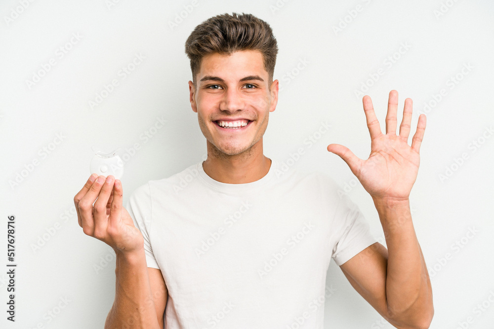 Young caucasian man hand sling isolated on white background smiling cheerful showing number five with fingers. Young caucasian man hand sling isolated on white background smiling cheerful showing number five with fingers.