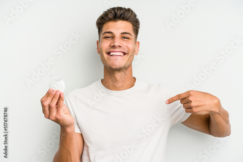 Young caucasian man hand sling isolated on white background person pointing by hand to a shirt copy space, proud and confident