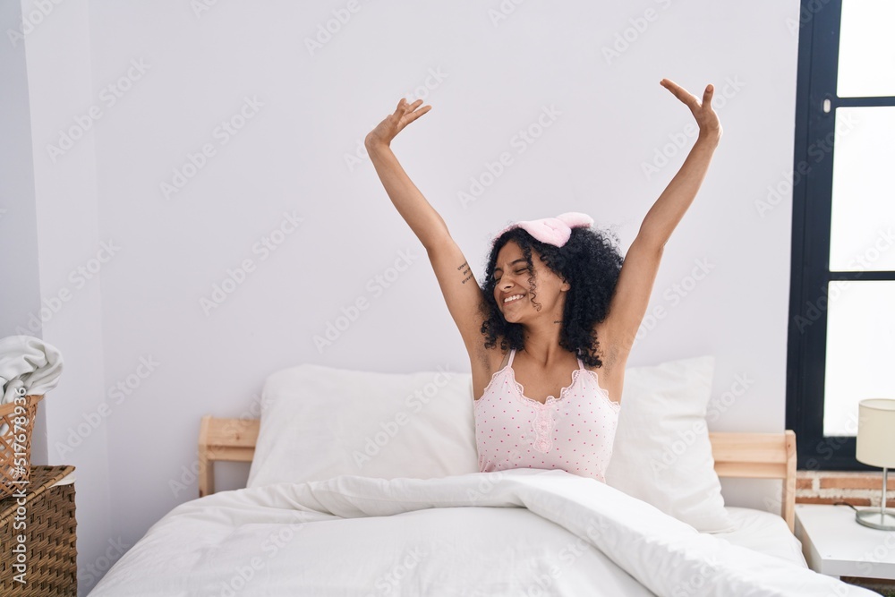 Young hispanic woman waking up stretching arms at bedroom Young hispanic woman waking up stretching arms at bedroom