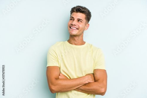 Young caucasian man isolated on blue background dreaming of achieving goals and purposes
