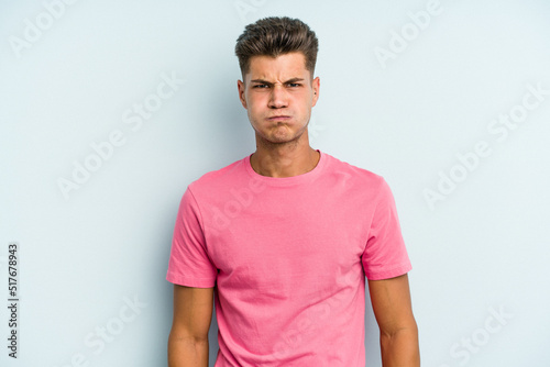 Wallpaper Mural Young caucasian man isolated on blue background blows cheeks, has tired expression. Facial expression concept. Torontodigital.ca