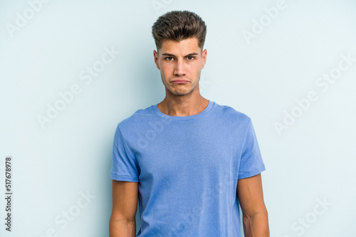 Young caucasian man isolated on blue background sad, serious face, feeling miserable and displeased.