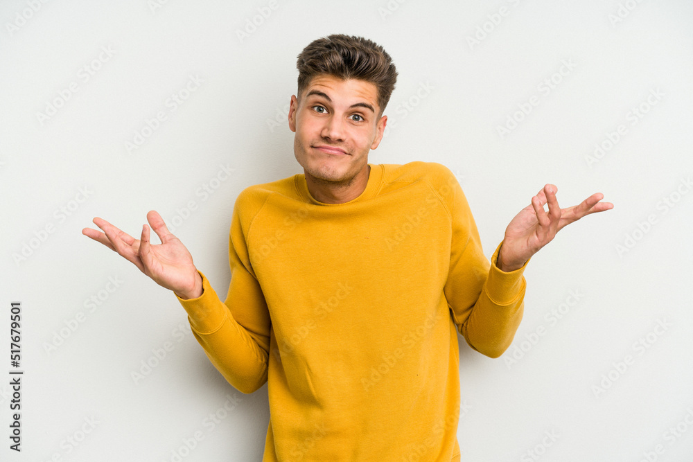 Young caucasian man isolated on white background doubting and shrugging shoulders in questioning gesture. Young caucasian man isolated on white background doubting and shrugging shoulders in questioning gesture.