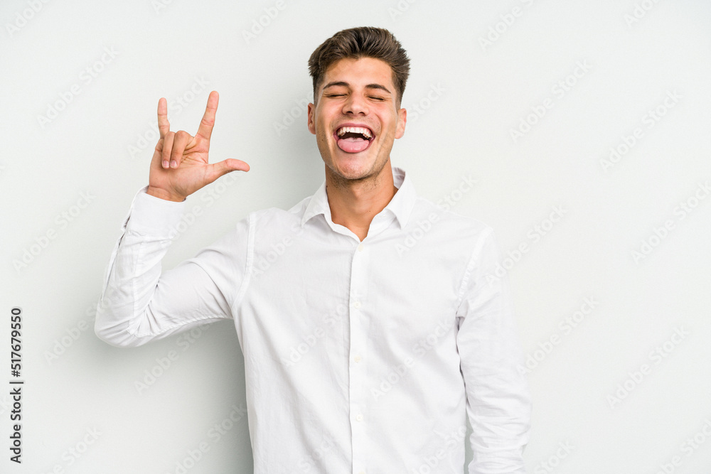 Young caucasian man isolated on white background showing rock gesture with fingers Young caucasian man isolated on white background showing rock gesture with fingers