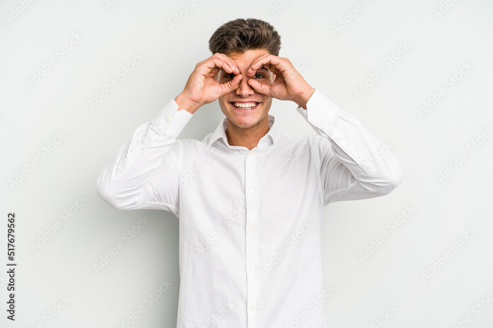Young caucasian man isolated on white background showing okay sign over eyes Young caucasian man isolated on white background showing okay sign over eyes