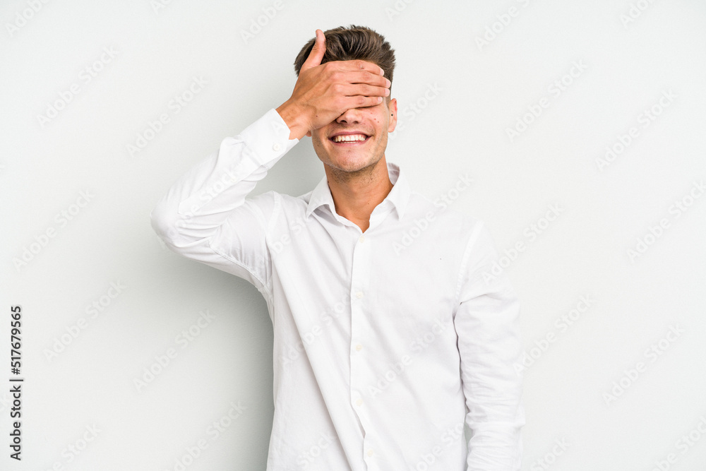 Young caucasian man isolated on white background covers eyes with hands, smiles broadly waiting for a surprise. Young caucasian man isolated on white background covers eyes with hands, smiles broadly waiting for a surprise.