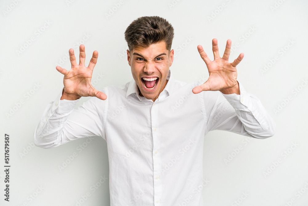 Young caucasian man isolated on white background showing claws imitating a cat, aggressive gesture. Young caucasian man isolated on white background showing claws imitating a cat, aggressive gesture.