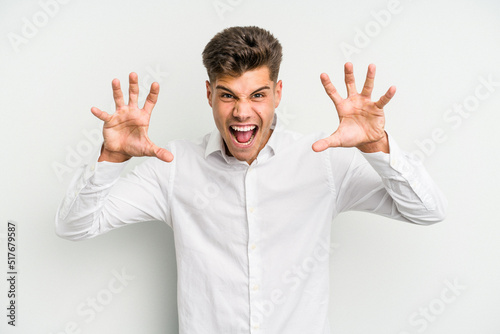Young caucasian man isolated on white background showing claws imitating a cat, aggressive gesture. © Asier