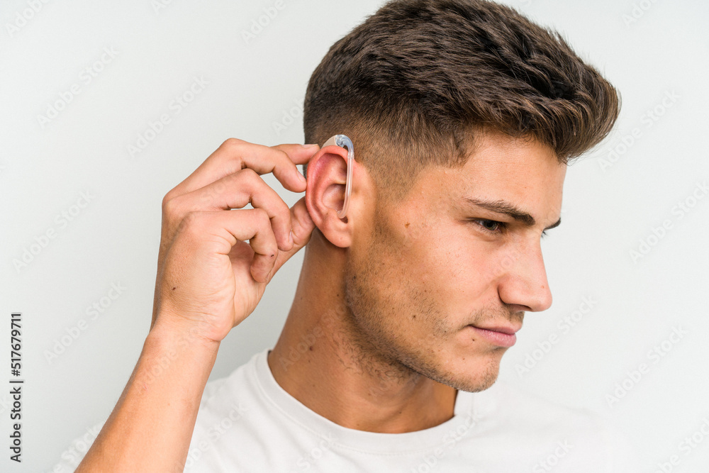 Young caucasian man wearing a hearing aid isolated on white background Young caucasian man wearing a hearing aid isolated on white background