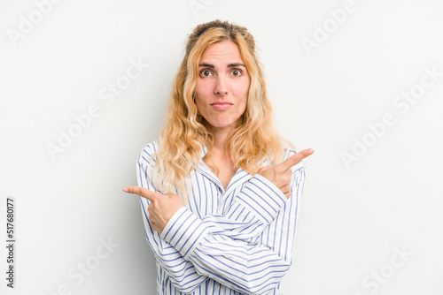 Young caucasian woman isolated on white background points sideways, is trying to choose between two options.