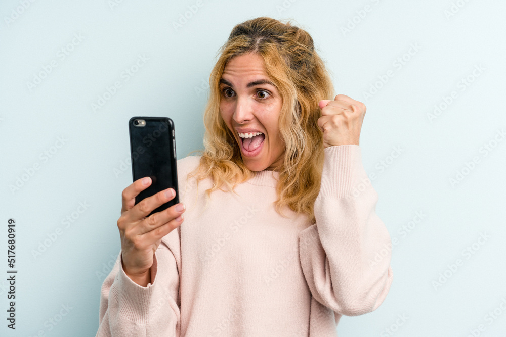 Young caucasian woman holding mobile phone isolated on blue background Young caucasian woman holding mobile phone isolated on blue background