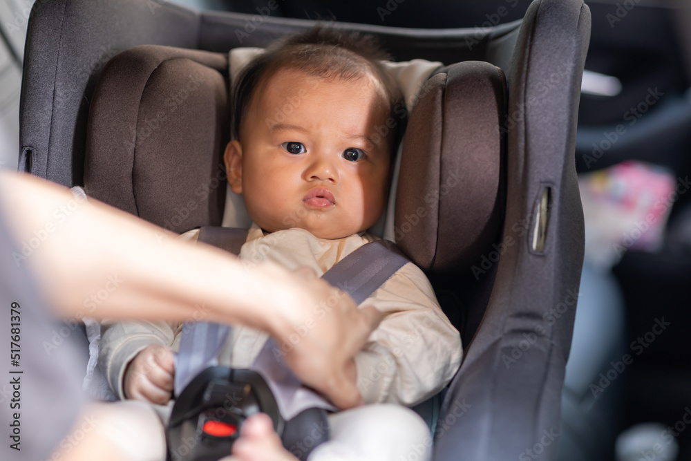 Mother put cute baby to car seat and secure with safety belts. Asian infant baby sit in baby seat and looking around in car.mom buckling her son to car seat.Baby safety on car concept Mother put cute baby to car seat and secure with safety belts. Asian infant baby sit in baby seat and looking around in car.mom buckling her son to car seat.Baby safety on car concept