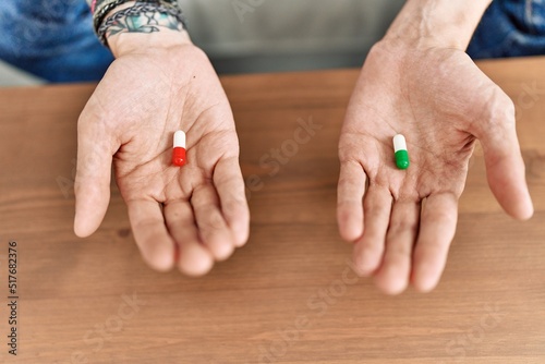 Hands of man holding pills sitting on the sofa at home