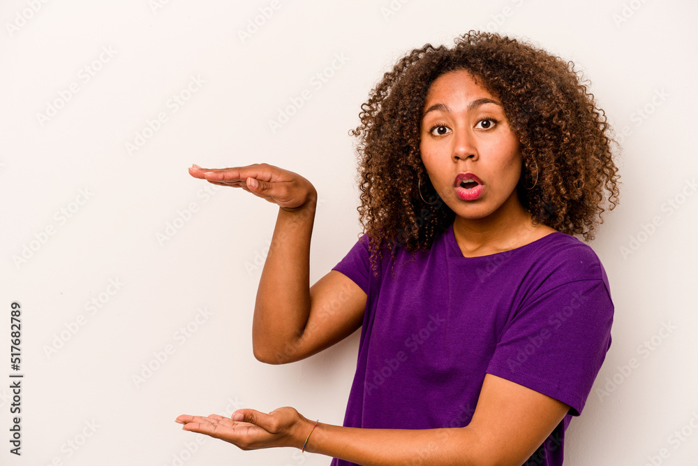 Young African American woman isolated on white background shocked and amazed holding a copy space between hands. Young African American woman isolated on white background shocked and amazed holding a copy space between hands.