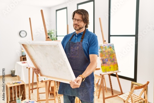 Middle age caucasian man smiling confident looking draw canvas at art studio