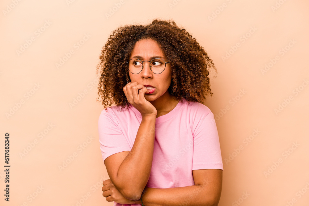 Young African American woman isolated on beige background biting fingernails, nervous and very anxious. Young African American woman isolated on beige background biting fingernails, nervous and very anxious.