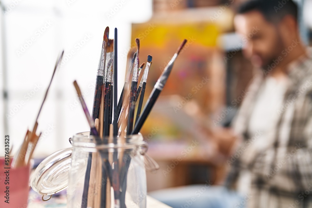 Fototapeta premium Young hispanic man drawing on notebook at art studio