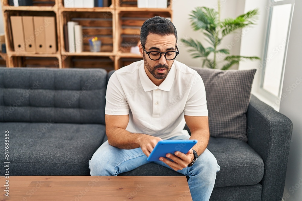 Young hispanic man psychologist having therapy session using touchpad at psychology center Young hispanic man psychologist having therapy session using touchpad at psychology center