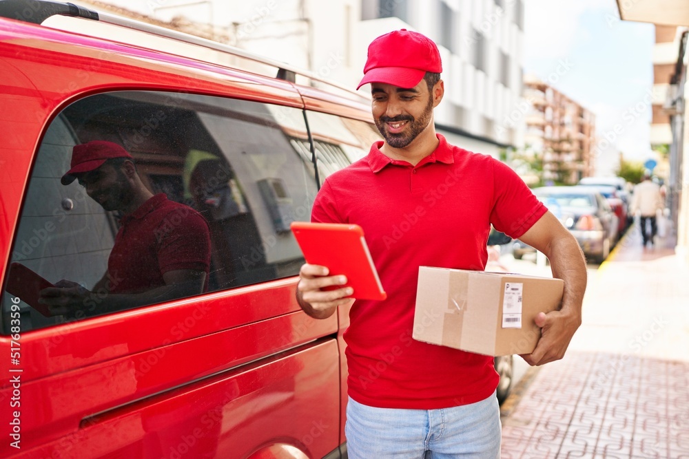 Young hispanic man courier using touchpad holding package at street