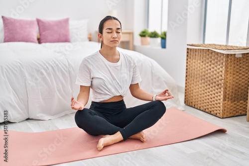 Young hispanic woman training yoga at bedroom