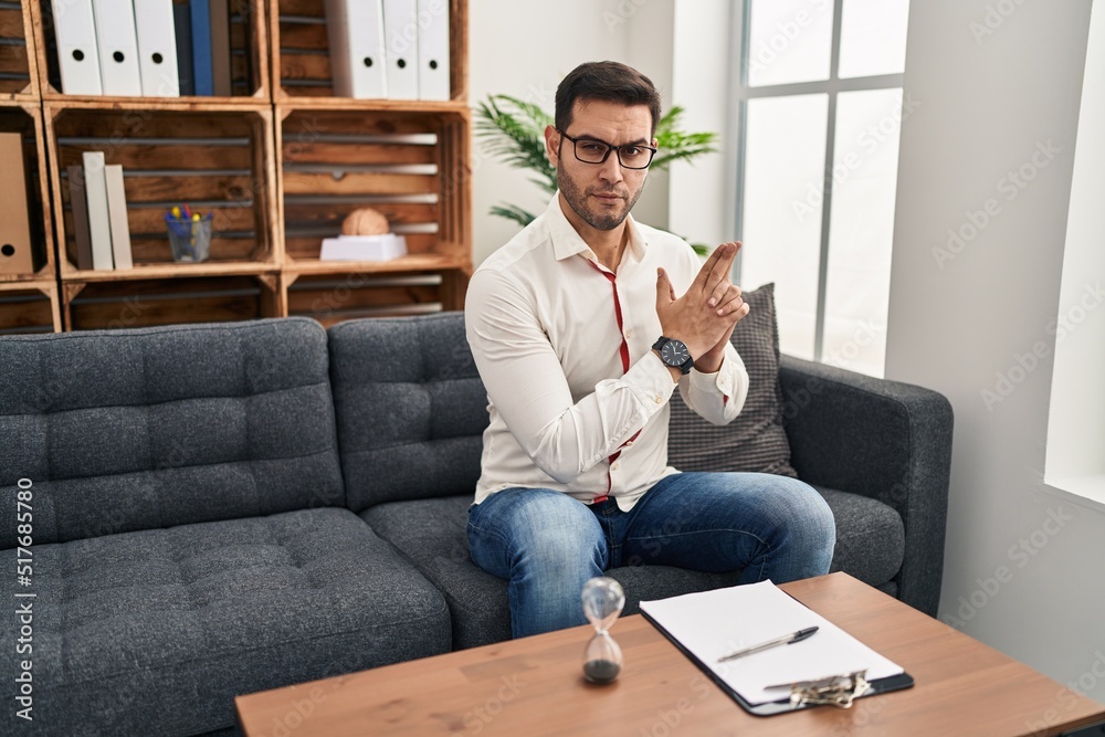 Young hispanic man with beard working at consultation office holding symbolic gun with hand gesture, playing killing shooting weapons, angry face Young hispanic man with beard working at consultation office holding symbolic gun with hand gesture, playing killing shooting weapons, angry face