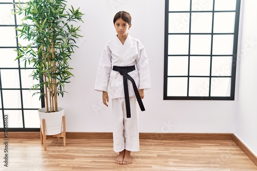 Young hispanic girl wearing karate kimono and black belt depressed and worry for distress, crying angry and afraid. sad expression.