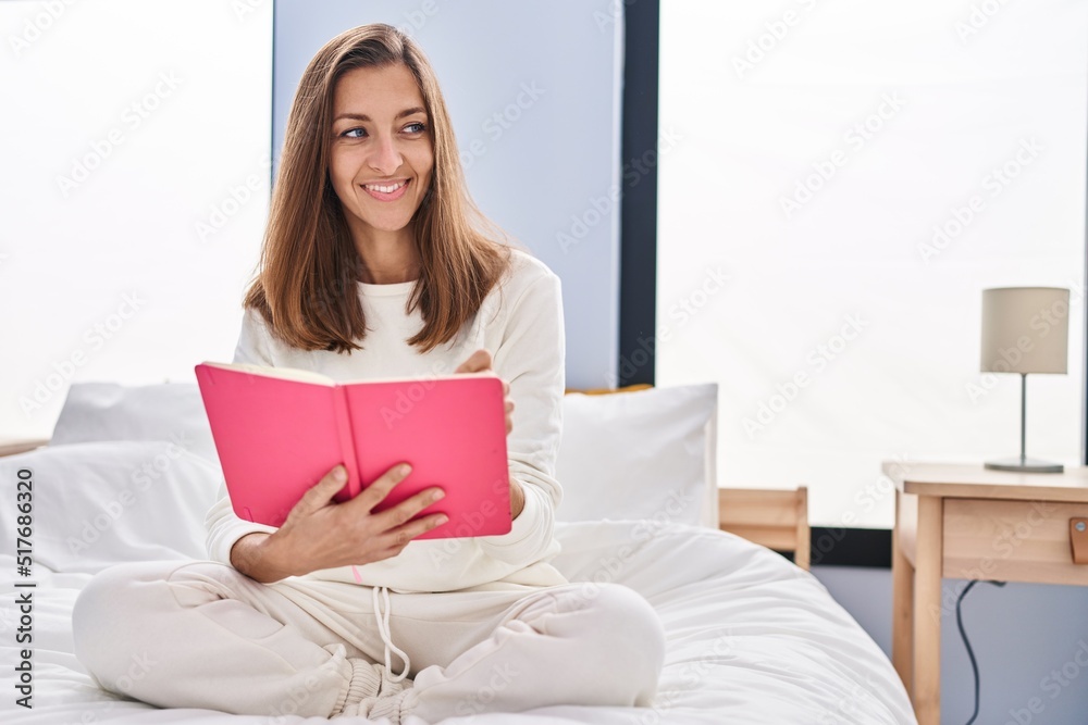 Young woman reading book sitting on bed at bedroom Young woman reading book sitting on bed at bedroom