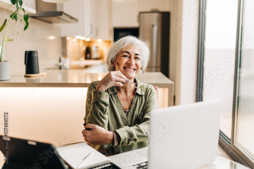 Mature entrepreneur smiling happily in her home office