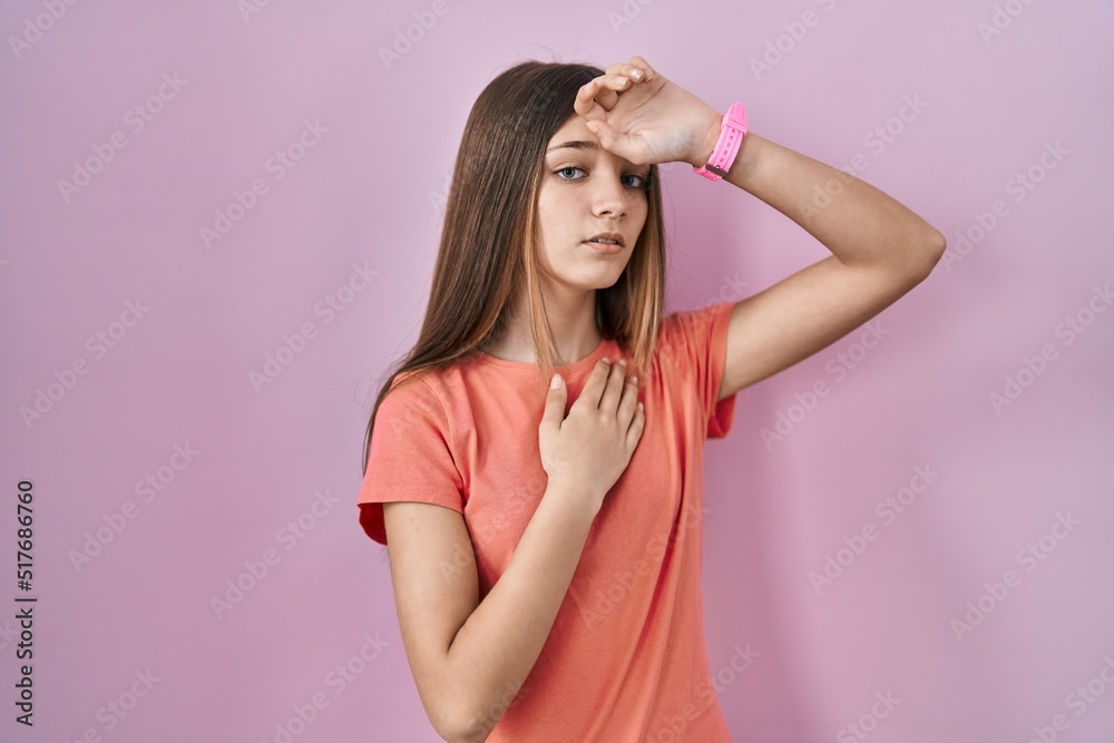 Teenager girl standing over pink background touching forehead for illness and fever, flu and cold, virus sick Teenager girl standing over pink background touching forehead for illness and fever, flu and cold, virus sick