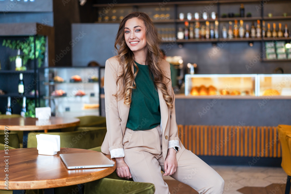 Business Woman Restaurant Owner With Laptop In Hands Dressed Elegant Pantsuit Sitting On Table In Restaurant With Bar Counter Background Business Woman Restaurant Owner With Laptop In Hands Dressed Elegant Pantsuit Sitting On Table In Restaurant With Bar Counter Background